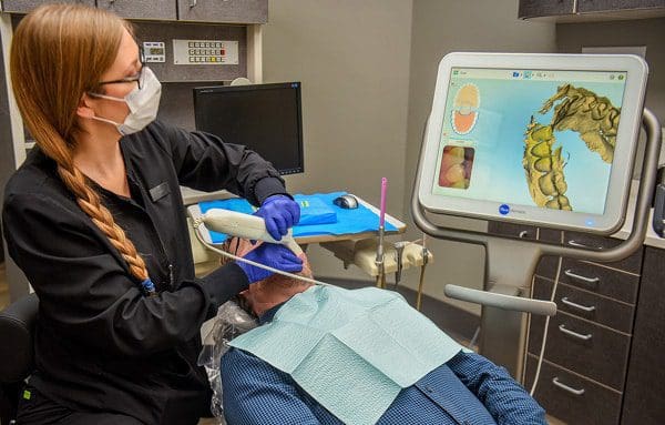 A masked woman sits calmly in a dental chair during her appointment.